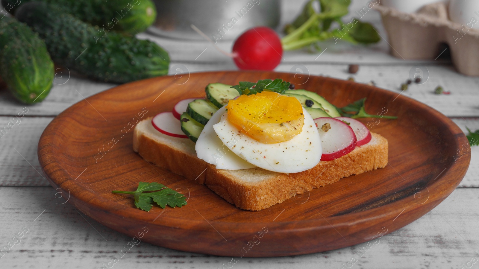 Photo of Tasty sandwich with boiled egg, radish and cucumber on white wooden table, closeup