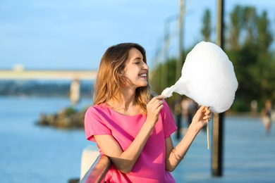 Happy young woman with cotton candy on waterfront