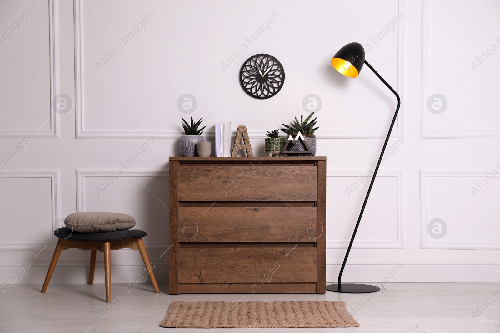 Photo of Stylish room interior with wooden chest of drawers near white wall