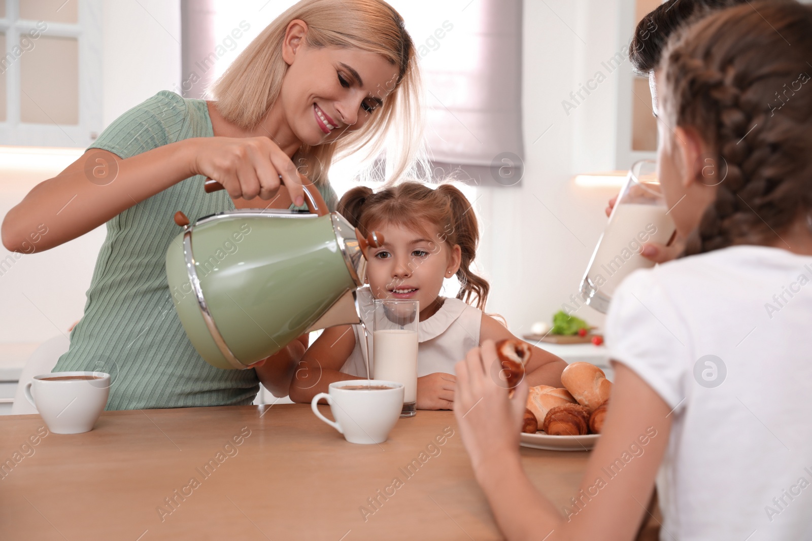 Photo of Happy family eating together at table in modern kitchen