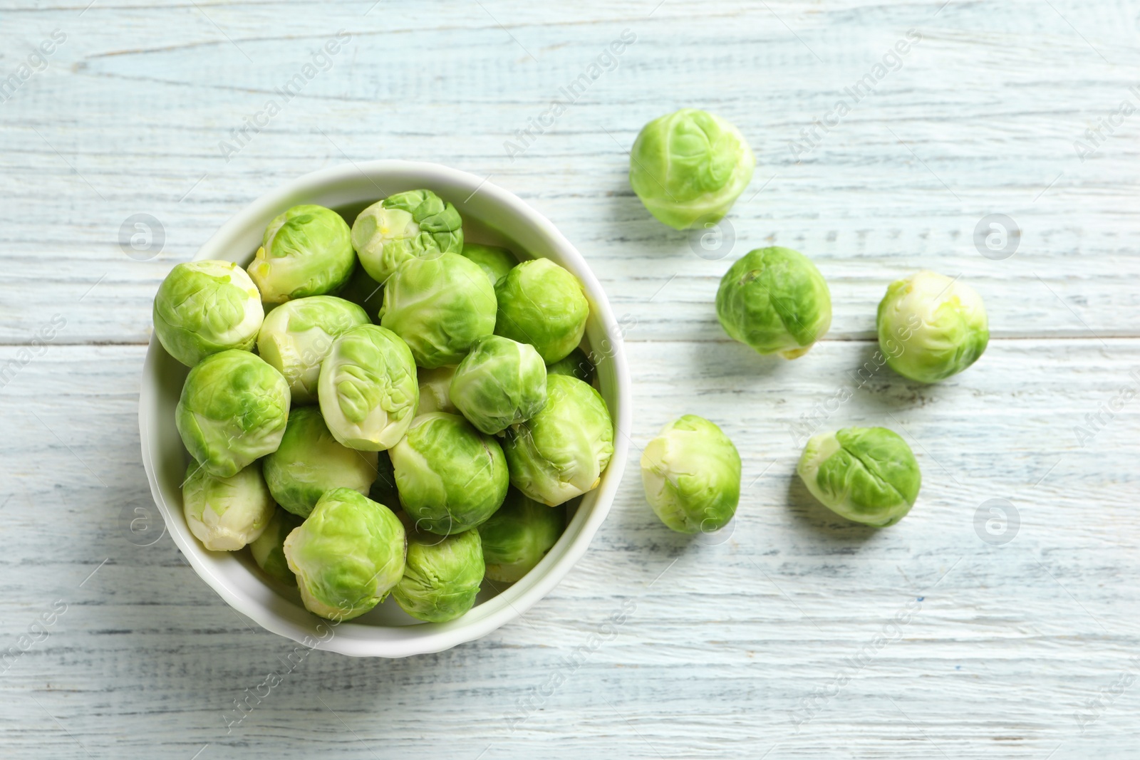 Photo of Bowl of fresh Brussels sprouts on wooden background, top view