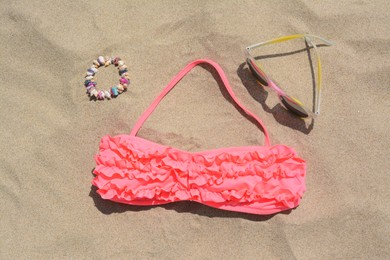 Photo of Sunglasses, bra and bracelet on sand, flat lay. Beach accessories