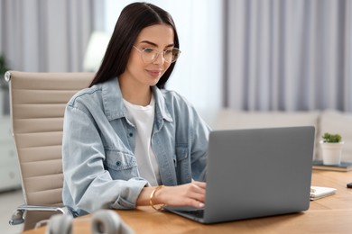 Young woman watching webinar at table in room