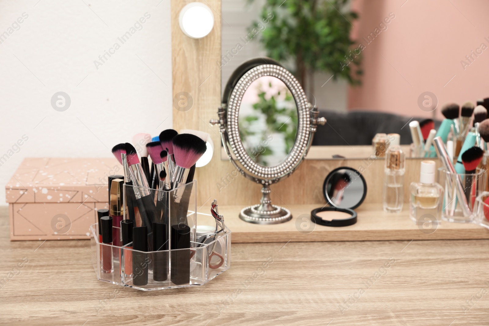 Photo of Organizer with cosmetic products for makeup on table near mirror. Space for text