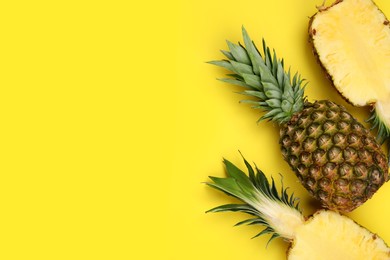 Whole and cut ripe pineapples on yellow background, flat lay. Space for text