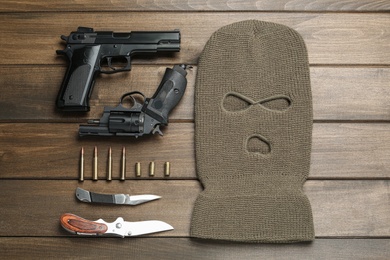 Photo of Flat lay composition with balaclava and weapons on wooden table