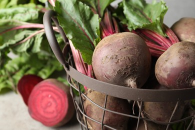 Photo of Fresh red beets with leaves in basket, closeup