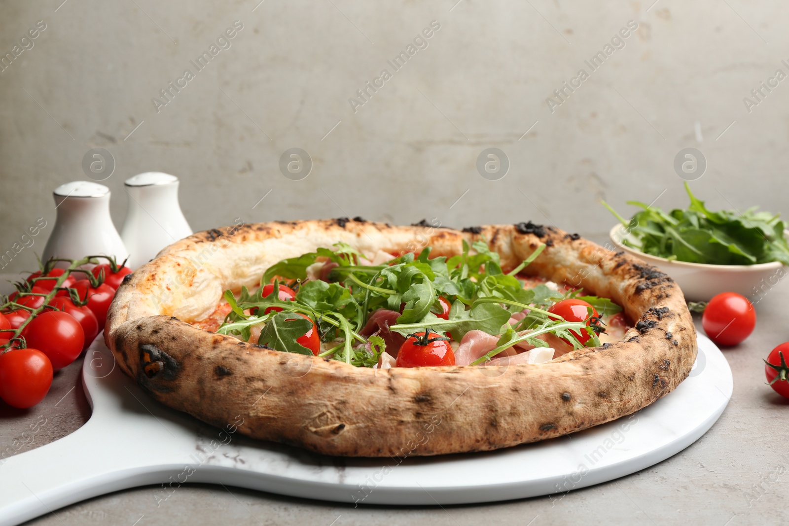 Photo of Tasty pizza with meat and arugula on grey table