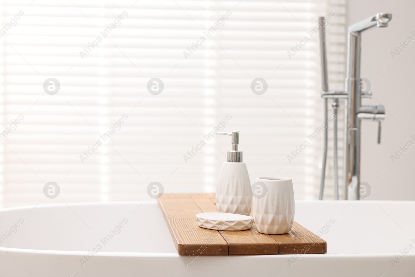 Photo of Set of bath accessories on tub in bathroom, space for text