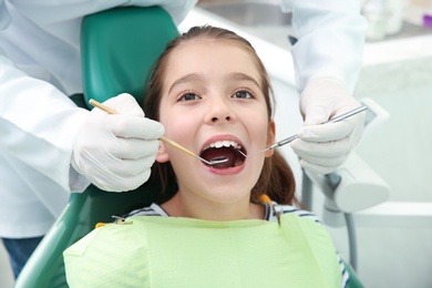 Photo of Professional dentist working with little patient in modern clinic