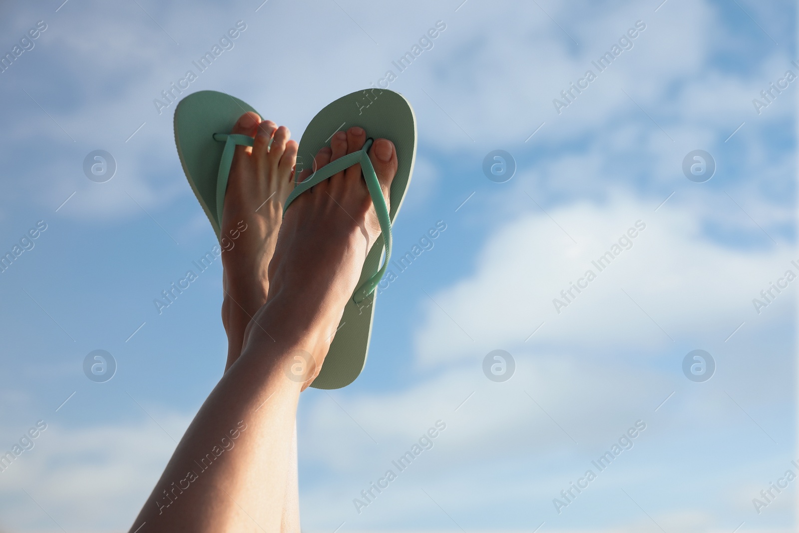 Photo of Woman in stylish flip flops against cloudy sky, closeup. Space for text