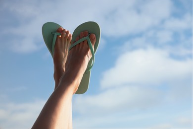 Photo of Woman in stylish flip flops against cloudy sky, closeup. Space for text