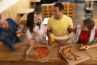 Photo of Group of friends having fun party with delicious pizza in cafe