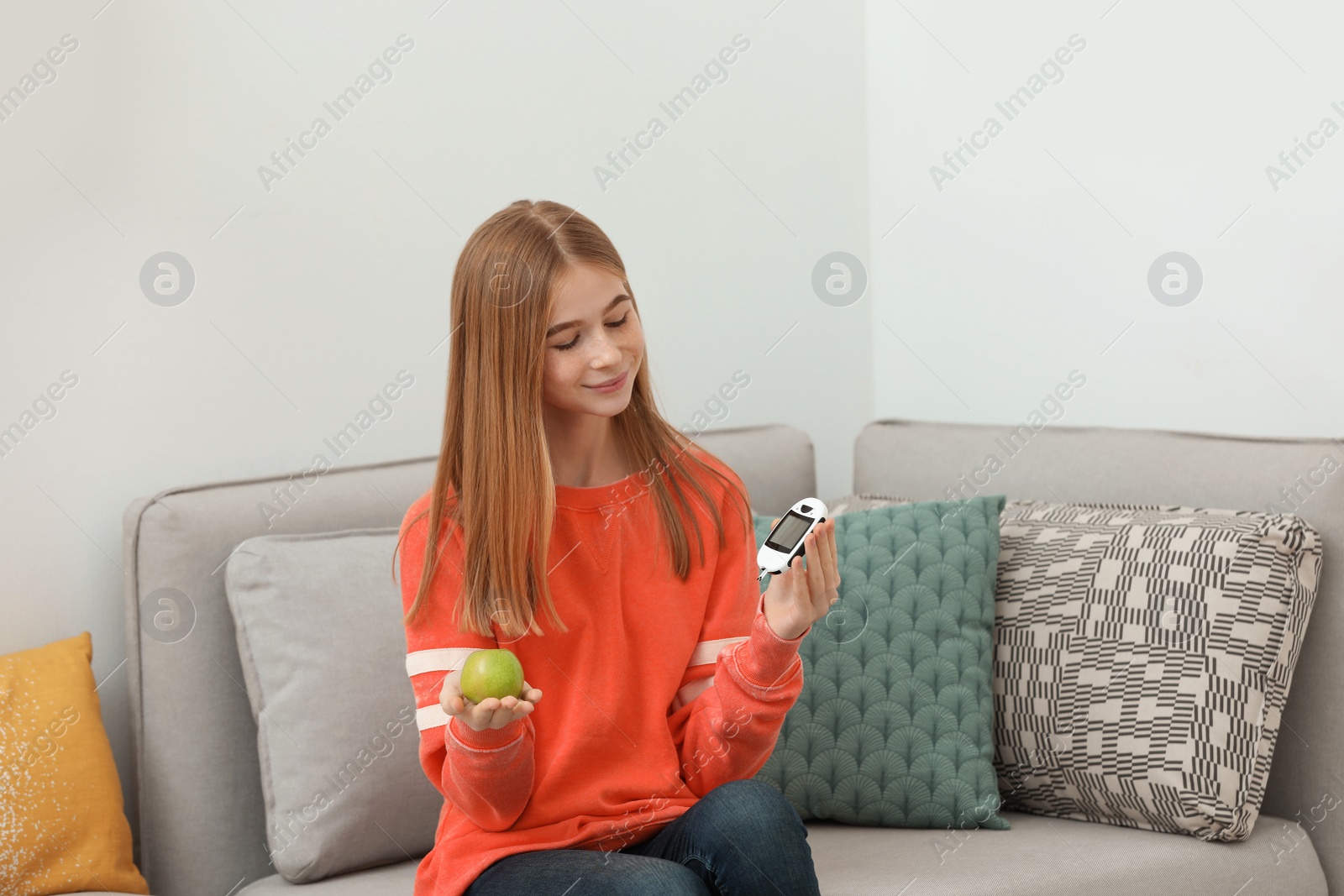 Photo of Teen girl holding digital glucometer and apple at home. Diabetes diet