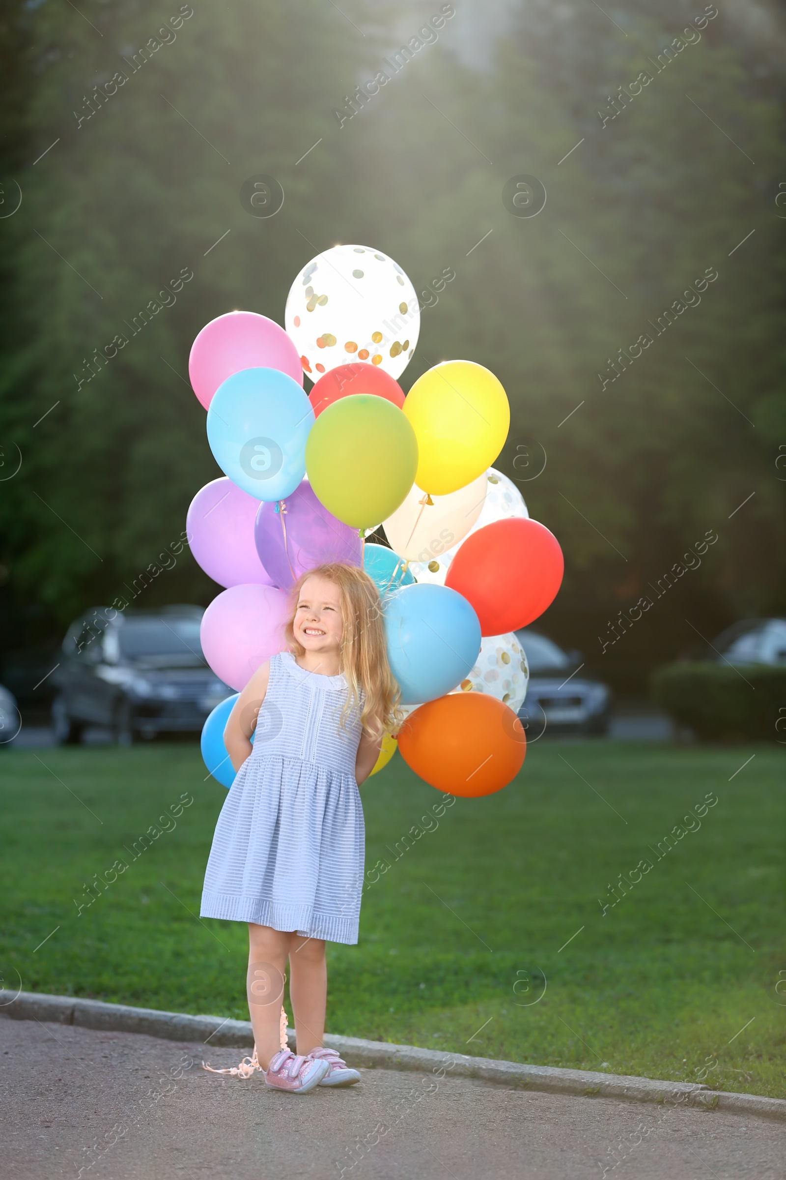 Photo of Cute girl with colorful balloons in park on sunny day