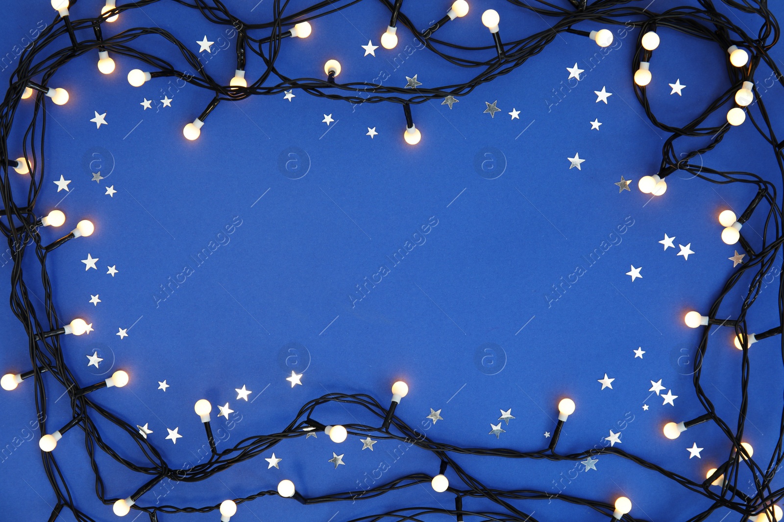 Photo of Glowing Christmas lights on color background, top view