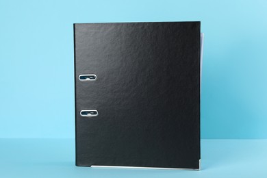 Photo of Black hardcover office folder on light blue background