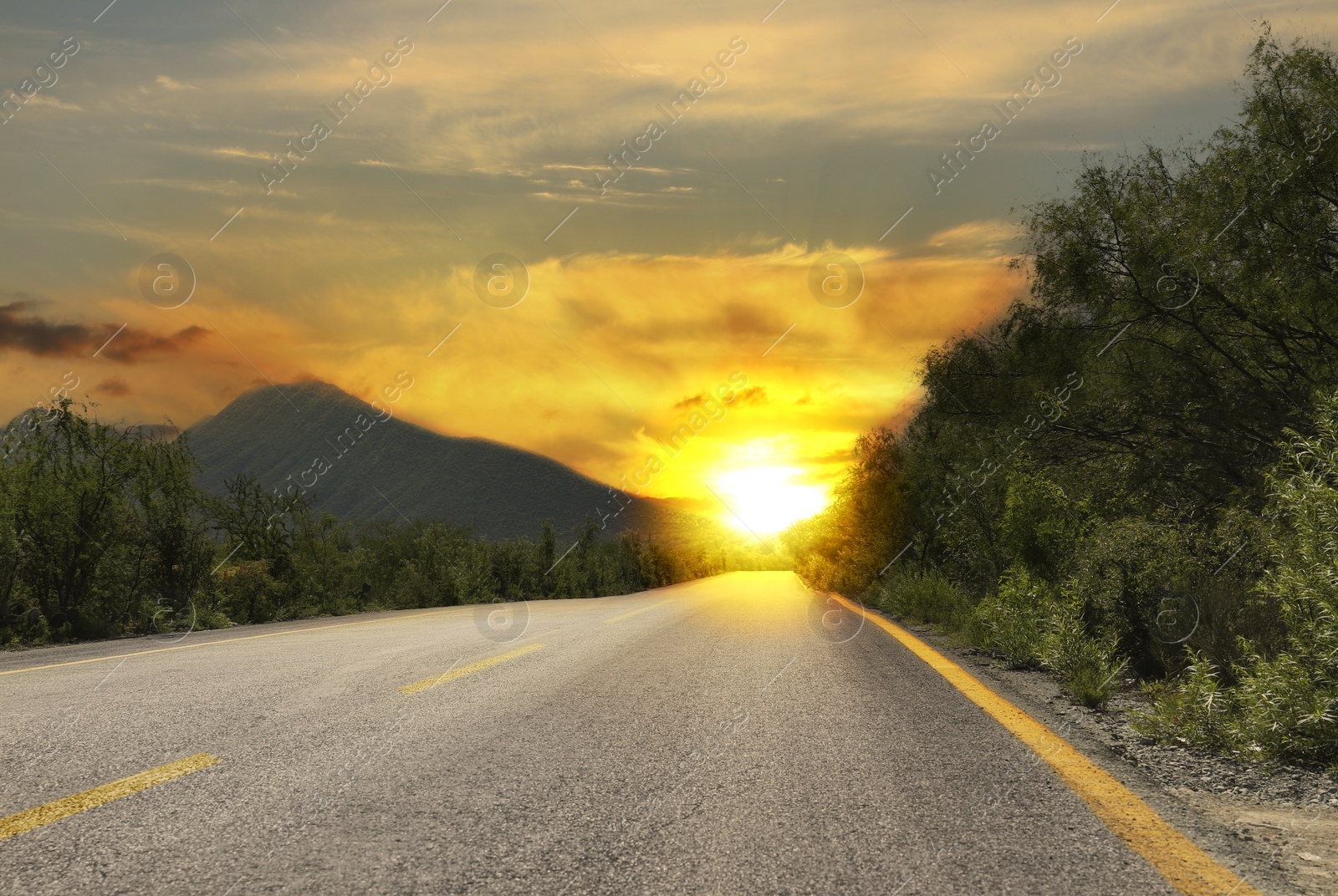 Image of Empty asphalt road, trees and mountains at beautiful sunset