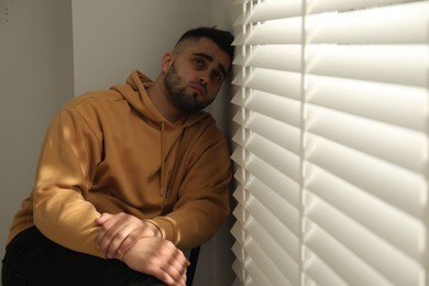 Photo of Sad young man and sitting near window