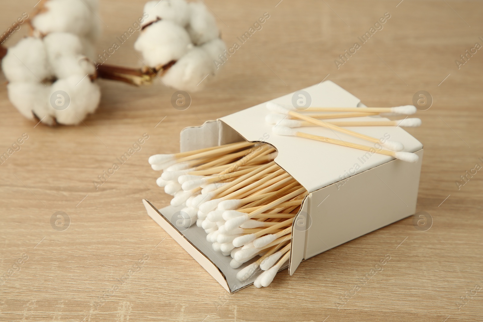 Photo of Cotton swabs and flowers on wooden table, closeup