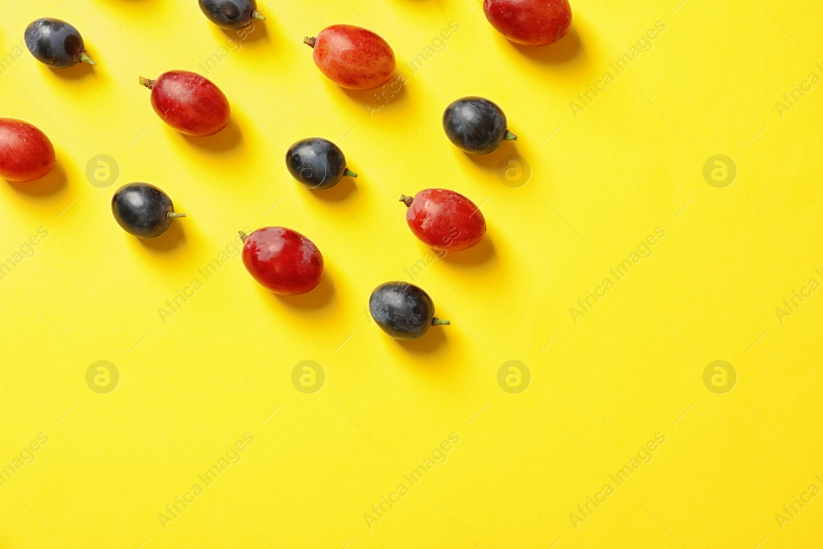 Photo of Fresh ripe juicy grapes on yellow background, top view. Space for text