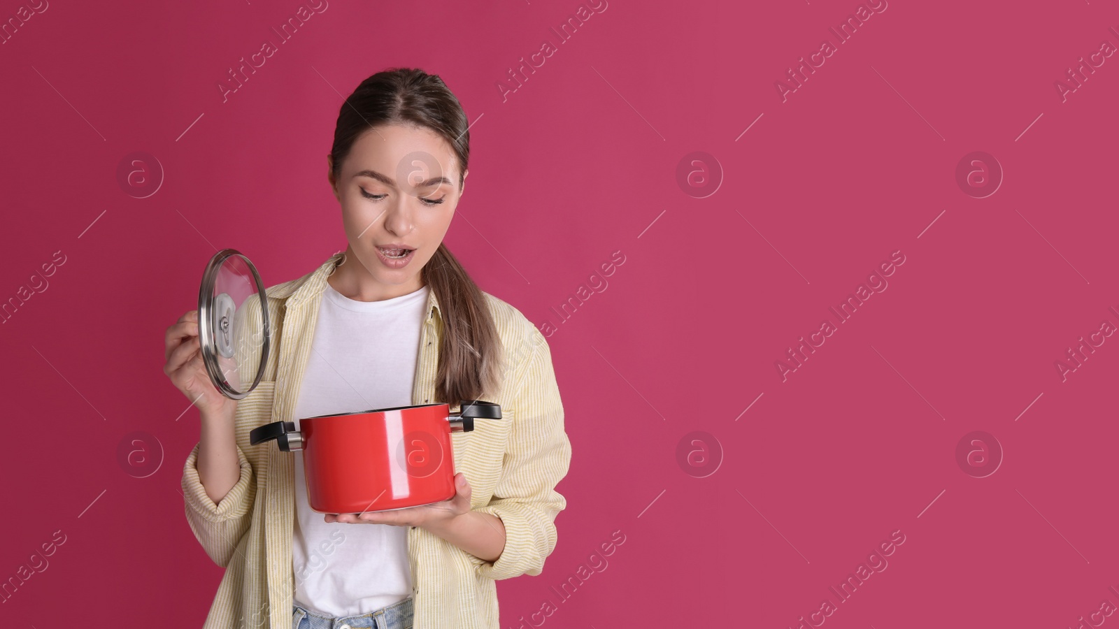 Photo of Surprised woman with pot on crimson background, space for text