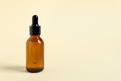 Bottle with cosmetic oil on beige background, closeup. Space for text