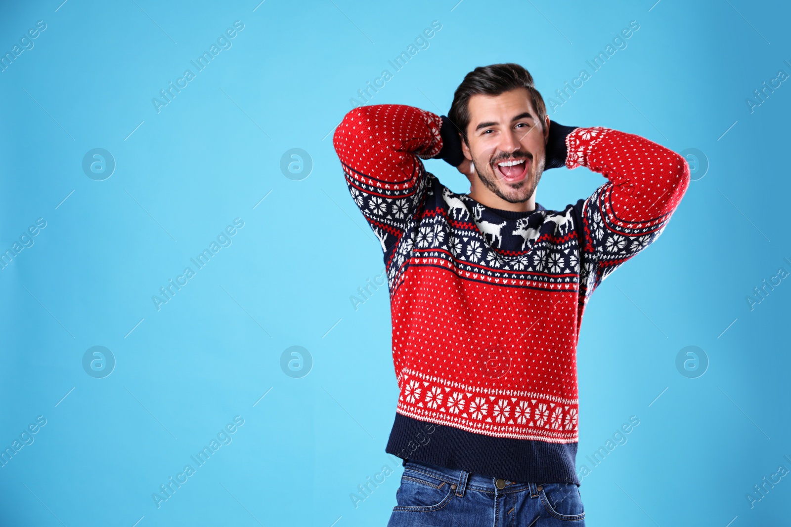 Photo of Portrait of happy young man in Christmas sweater on light blue background. Space for text