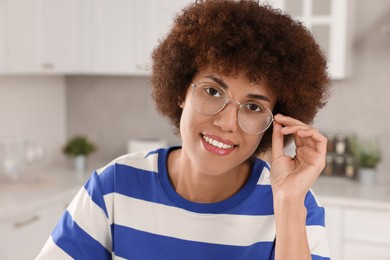 Photo of Portrait of happy young woman with eyeglasses in kitchen