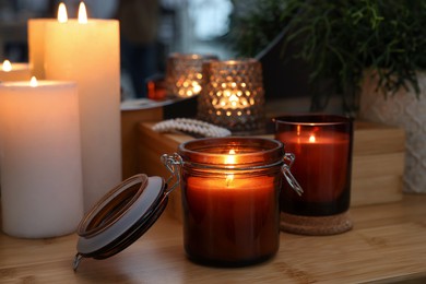 Photo of Lit candles on wooden dressing table indoors