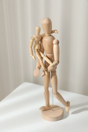 Photo of Wooden mannequins of parent with child on white table against light background. Family Day