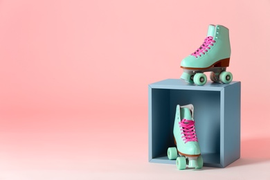 Photo of Pair of vintage roller skates and storage cube on color background. Space for text