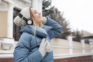 Young woman with headphones listening to music outdoors. Space for text