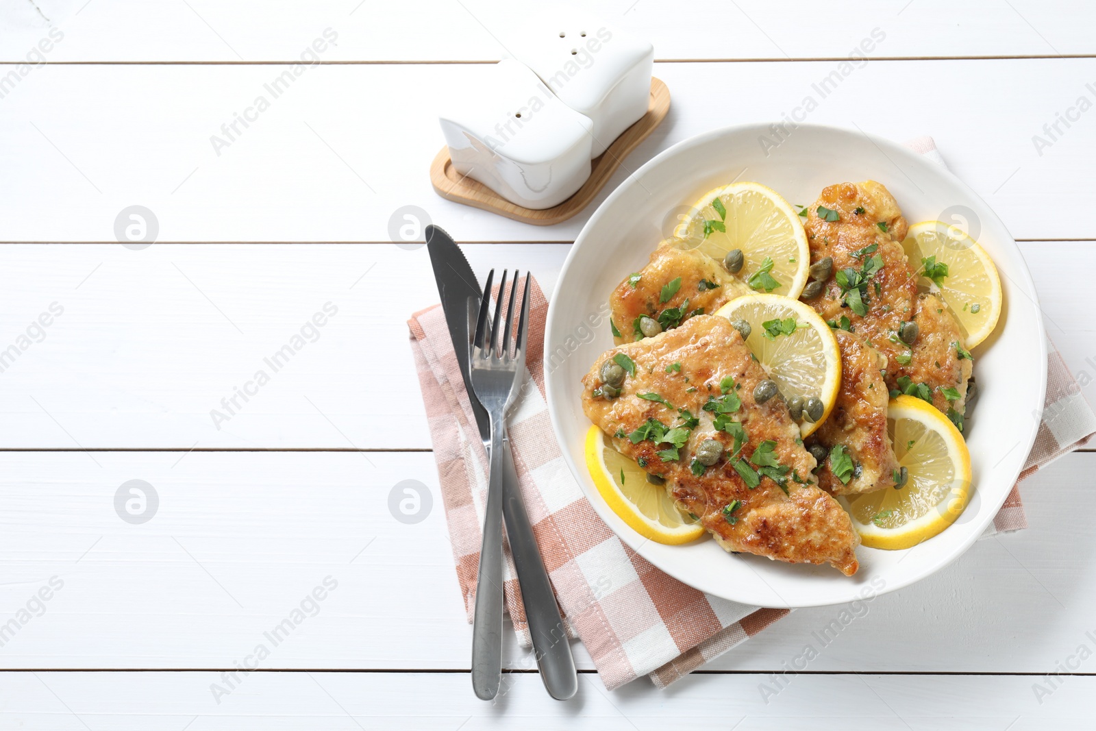 Photo of Delicious chicken piccata served on white wooden table, flat lay. Space for text