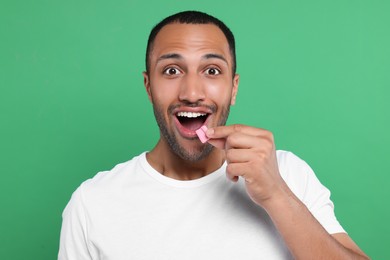 Photo of Portrait of excited young man with bubble gum on green background