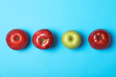 Photo of Row of red apples with green one on color background, top view. Be different