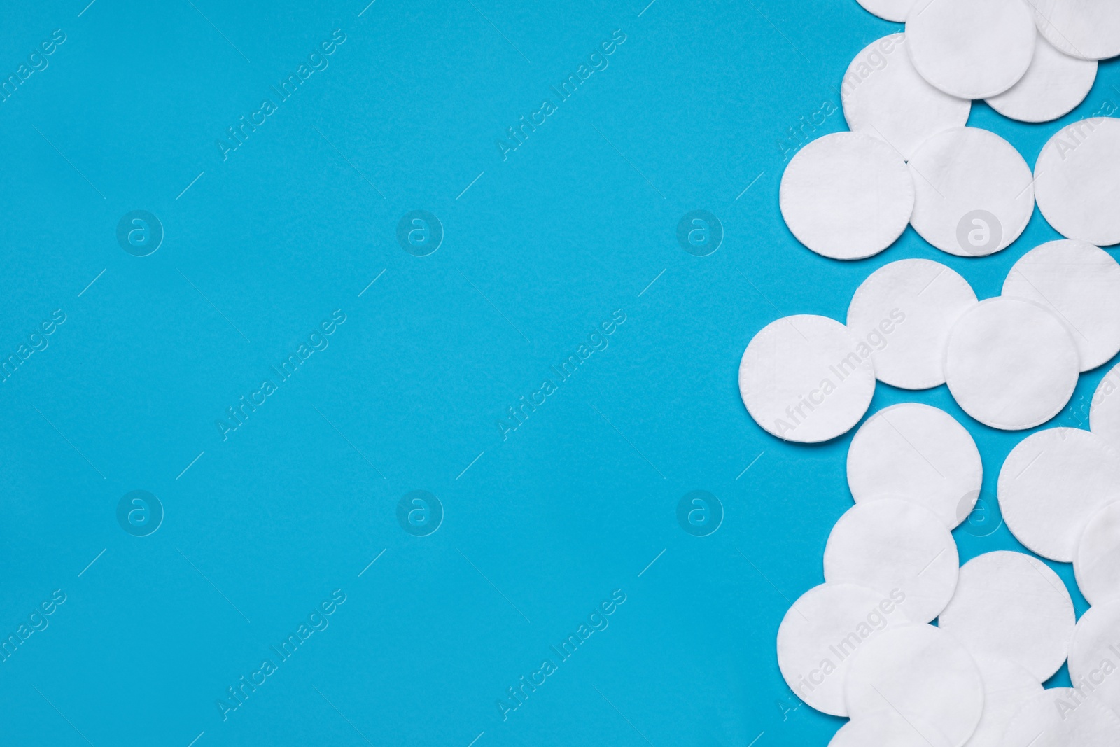 Photo of Many cotton pads on light blue background, flat lay. Space for text