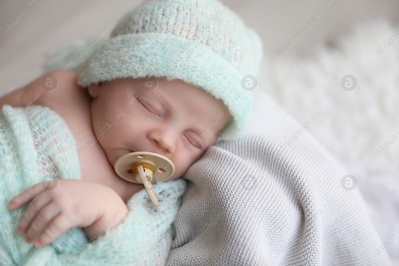 Photo of Cute newborn baby in warm hat sleeping on plaid, above view