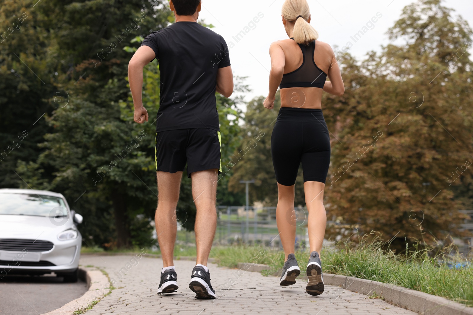 Photo of Healthy lifestyle. Sporty couple running outdoors, back view