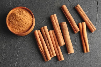 Photo of Aromatic cinnamon sticks and powder on dark grey background