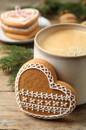 Photo of Tasty heart shaped gingerbread cookie and hot drink on wooden table, closeup