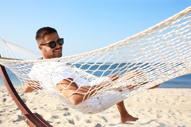 Young man relaxing in hammock on beach