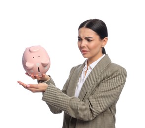 Sad young businesswoman with piggy bank on white background