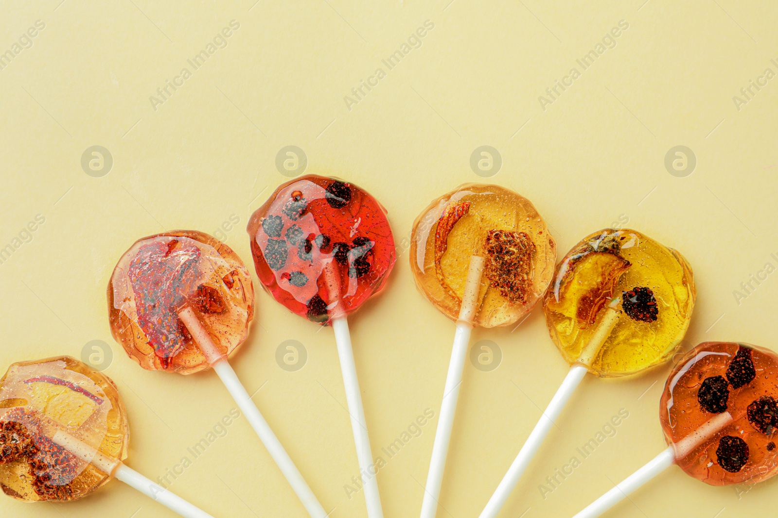 Photo of Sweet colorful lollipops with berries on beige background, flat lay