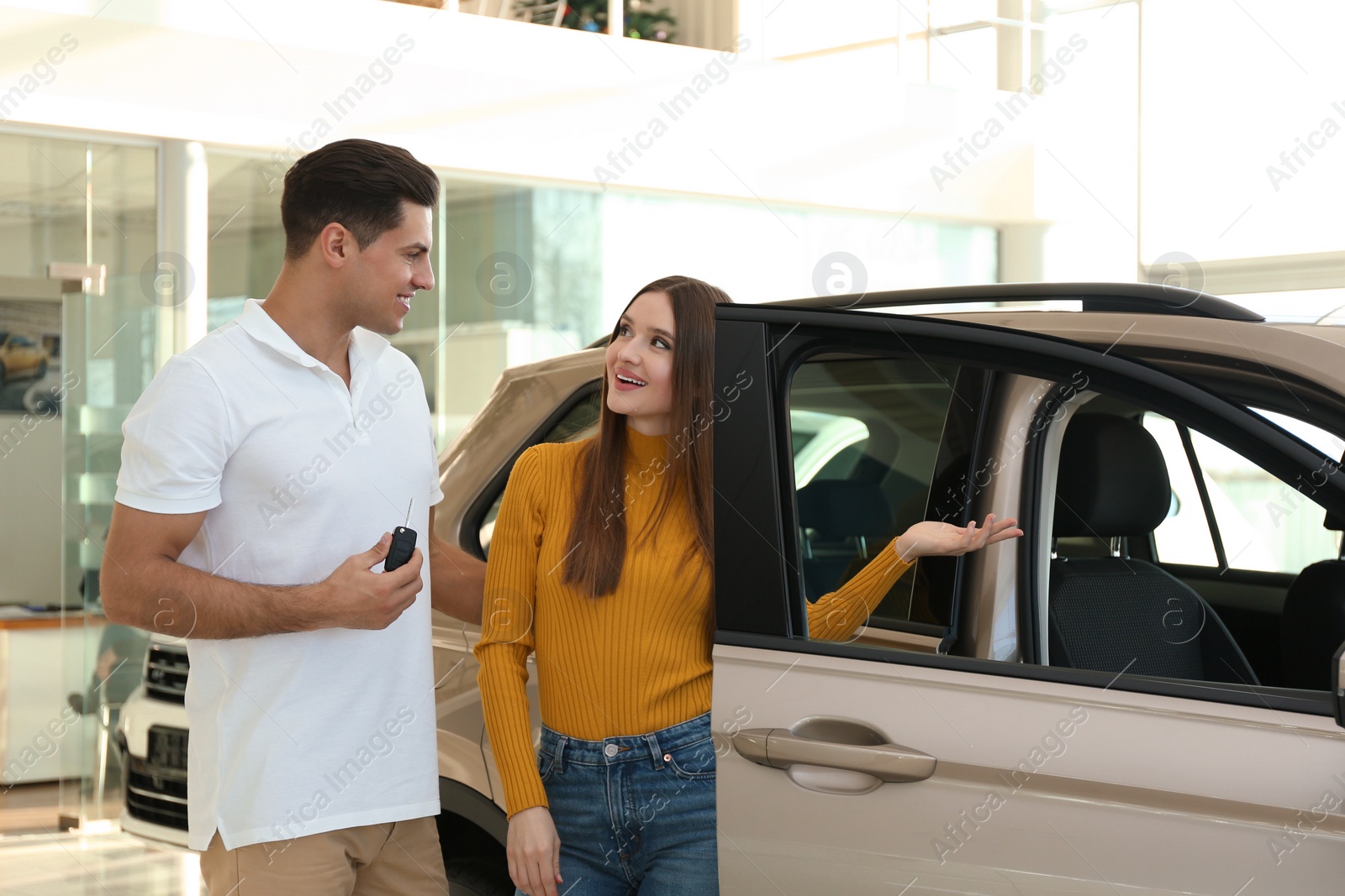 Photo of Happy couple with car key in modern auto dealership