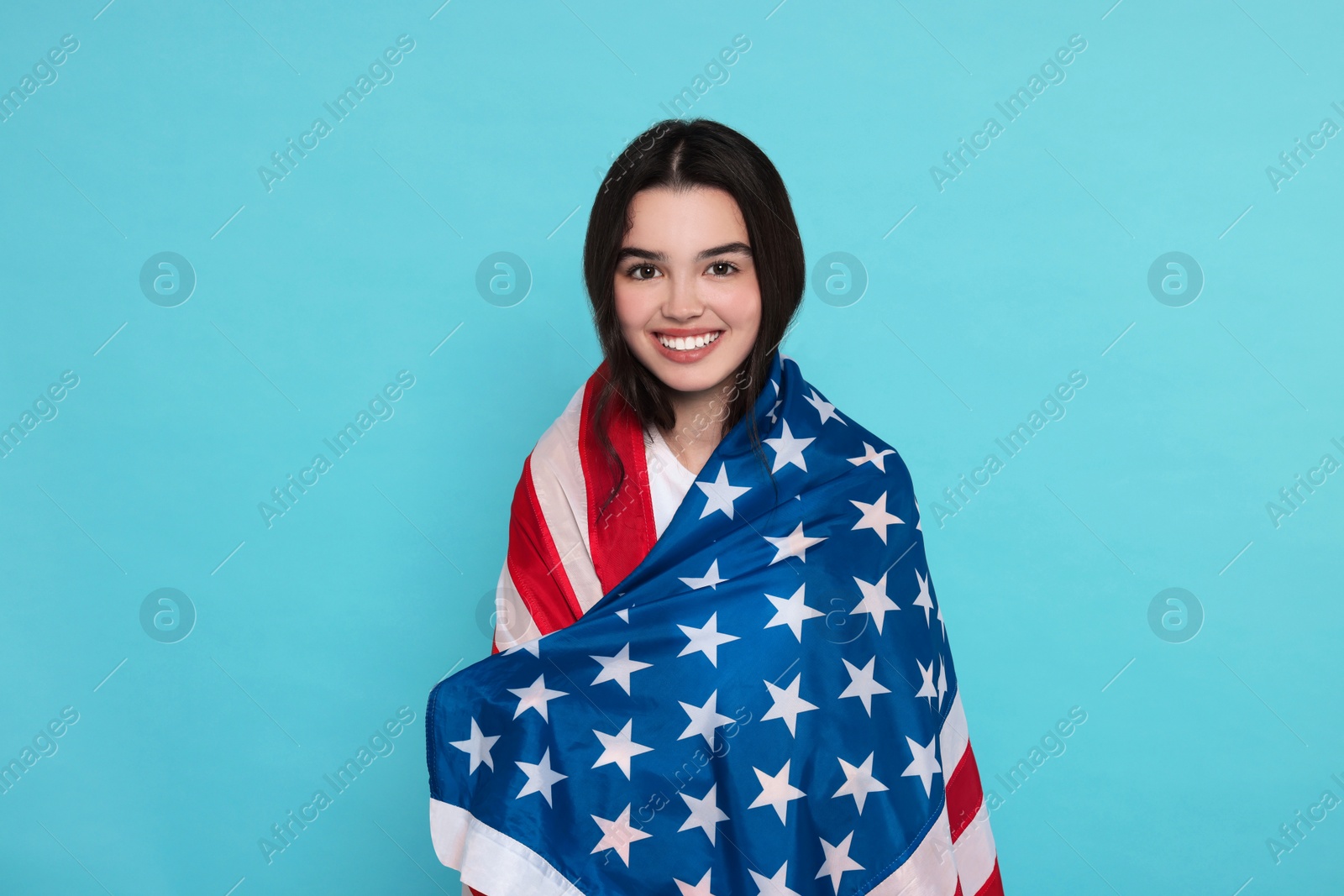 Photo of 4th of July - Independence Day of USA. Happy girl with American flag on light blue background