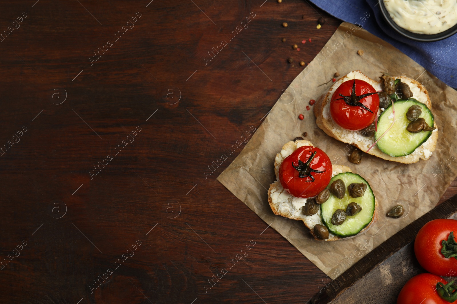 Photo of Tasty bruschettas with vegetables and capers on wooden table, flat lay. Space for text