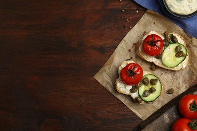 Tasty bruschettas with vegetables and capers on wooden table, flat lay. Space for text