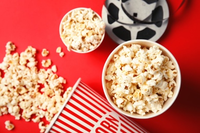 Photo of Tasty popcorn and film reel on color background, top view. Cinema snack