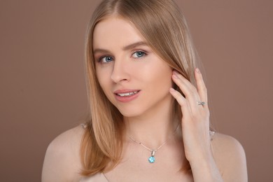 Beautiful young woman with elegant jewelry on light brown background